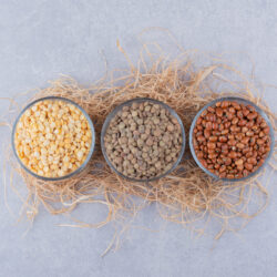 Lentils and red beans portioned into glass bowls on a pile of straw on marble background Lentils and red beans portioned into glass bowls on a pile of straw on marble background. High quality photo